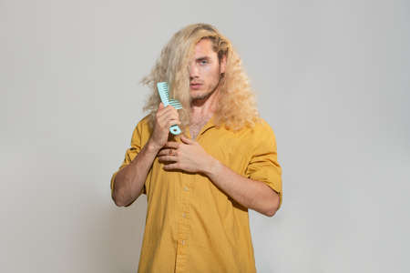 Portrait of handsome man combing hair. Close up hair styling, guy brush take hairdo isolated grey...