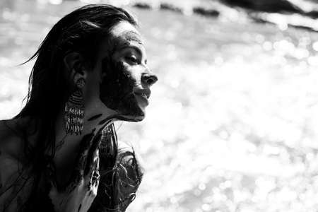 Dirty woman laying in the beach. Woman in medical mud. Girl enjoying the natural mineral mud. Dead Sea Mud bath Treatment.の写真素材