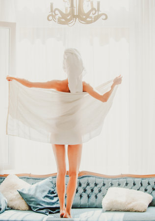 Perfect slim young woman body with towel of the girl after shower. Back view of sexy girl resting in the luxury bedroom after bath an morning.の写真素材
