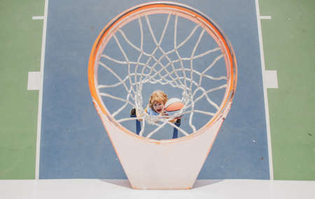 Kid playing basketball. Cheerful boy basketball player holding game ball.の写真素材