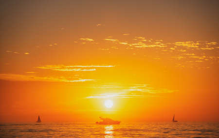 Calm golden sea with sunset sky and sun through the clouds over. Ocean and sky background, seascape.の写真素材