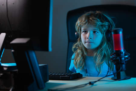 Child learning online at night, using desktop computer in living room at home. Child using computer...