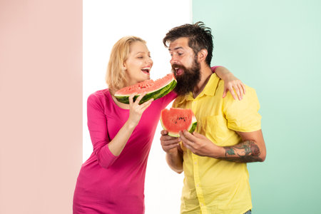 Two friends of woman and man enjoying a watermelon. Friends eating a watermelon slice and laughing together.の写真素材