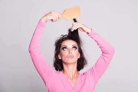 Woman combing hair. Portrait of female model with a comb brushing hair. Girl with hairbrush, hair care and beauty. Advertising for a beauty salonの写真素材