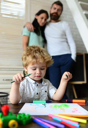 Kid learning painting, little artist painting, drawing. Happy family of three having fun together. Cheerful parents playing with son. Father mother and child drawing together at home.の写真素材