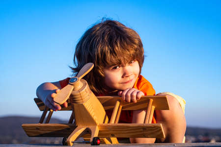 Funny child or kid little boy pilot play with toy airplane, startup freedom and carefree. Dreams of flight. Child playing with toy airplane against the sky. Cute kids face.の写真素材