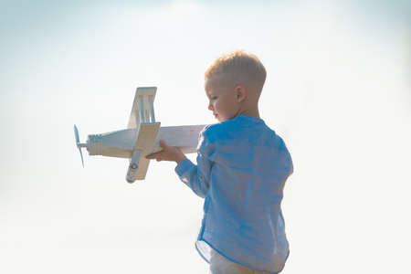 Child boy playing with wooden toy airplane, dream of becoming a pilot. Childrens dreams. Child pilot...