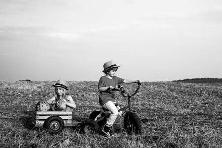 Freedom for children. Cute kids on retro bike against blue sky background on field. Kids love. Kid having fun at countryside.の写真素材