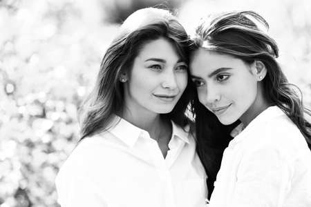 Girl couple spending time outside together. Happy women in a park on green spring background.