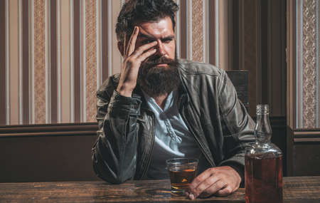 Man with beard holds glass brandy. Man holding a glass of whisky. Handsome stylish bearded man is drinking at home after work. Drunk man.の写真素材