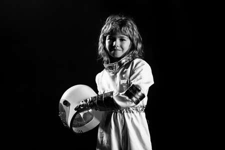 Little boy astronaut in space suit holding helmet on black.の写真素材