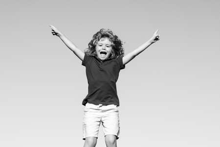 Portrait of a excited little boy on blue sky in the park.