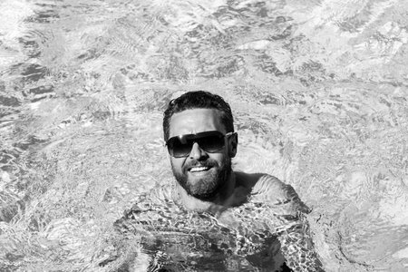 Handsome man in sunglasses. Summertime vacation. Pool party. Summer resort.の写真素材