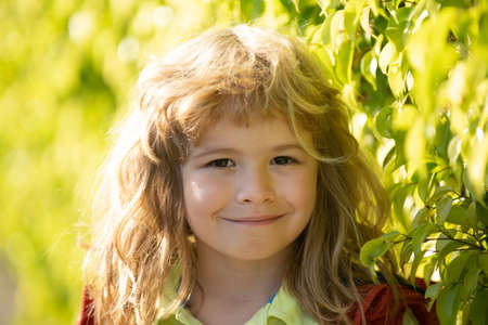 Happy smiling child, adorable lovely kid. Joyful portrait of small child on green nature background...