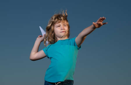 Kid boy throwing a paper plane with blue sky background.の写真素材