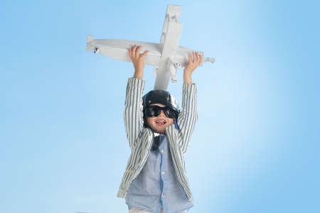 Child pilot with toy airplane dreams of traveling in summer in nature. Kids dreams. Child plays with a toy plane and dreams of becoming a pilot.の写真素材