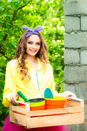 Teenager gardening during a nice summer day. Smiling teen girl with basket on garden nature background.の写真素材