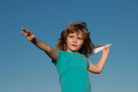 Kid boy throwing a paper plane with blue sky background.の写真素材