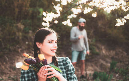 Young woman entrepreneur working in flower garden. Young woman holding tulips in the garden.