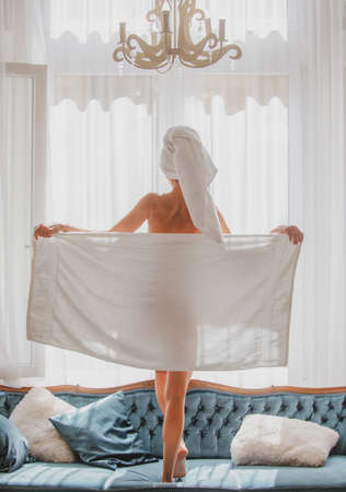 Perfect young woman body with towel after shower. Back view of sexy girl resting in the luxury bedroom an easy morning. Attractive sensual woman relaxing wearing bathrobes and towels in luxury room.の写真素材