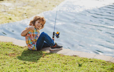 Happy childhood. Child fishing on the lake. Boy with spinner at river. Portrait of excited boy fishing. Boy at jetty with rod.の写真素材