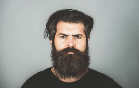 Portrait of confident serious man has beard and mustache, looks seriously, isolated. Hipster guy...
