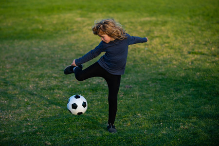 Soccer kid. Kids play football on summer stadium field. Little child boy kicking ball. Boy kicking football ball. Young boy with soccer ball doing flying kick.の写真素材