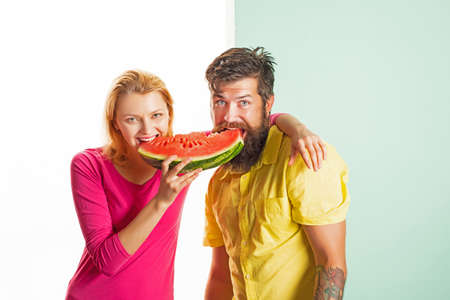 Young couple eating watermelon. The cheerful love couple eating slices of watermelon. Romantic...