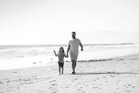 Father and son walking on sea. Dad and child holding hands and walk together. Happy family concept.の写真素材