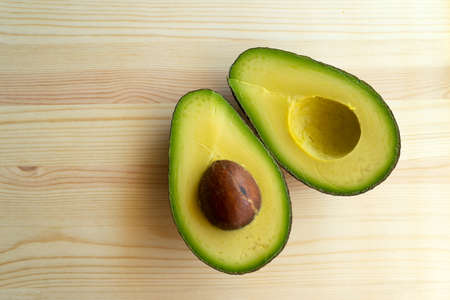 Avocado on wooden background. Avocado fruit. Raw healthy green food. Whole and half avocado.の写真素材