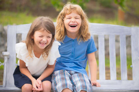 Two smiling laughing kids relaxing outdoors at summer park. Brother and sister happy walking in nature. Siblings boy and girl playing in garden.の写真素材