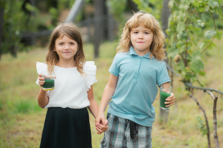 Happy brother and sister walking outdoors in summer park outdoors. Little boy and girl kids enjoying summer. Kids walking at backyard. Best friends two children.の写真素材