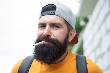 Handsome guy smoking outside in urban. Man smoking cigarette.の写真素材