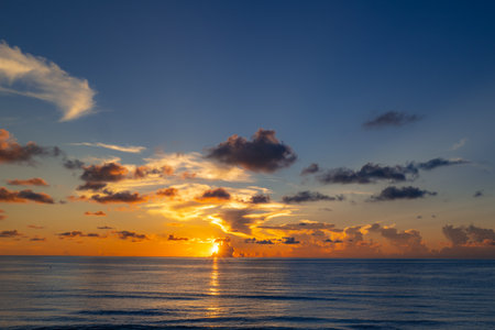 Sunset on tropical beach sea ocean with sunrise clouds. Banner for travel vacation. Scenery sky and reflection rays in water. Dusk, twilight on sea. Tranquil, golden sky background.の写真素材