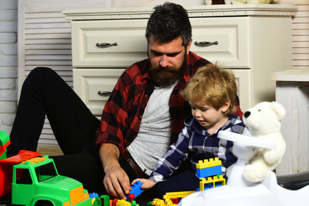 Father and son create toys from bricks. Dad and kid build of plastic blocks. Family daddy child leisure game. Loving dad and little boy child have fun play build construct with wooden blocks bricks.の写真素材