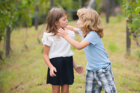 Adorable happy kids outdoors on summer day, little boy kissing a girl. Lovely little boy and girl, have fun and hugging outdoor. Funny kids face.の写真素材