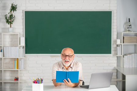 Adult teaching. Portrait of senior teacher teaching line of high school students with notebook in classroom on blackboard.の写真素材