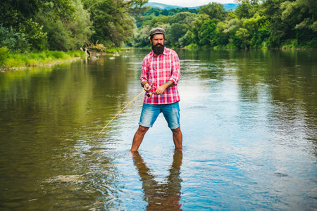 Young bearded man fishing at a lake or river. Flyfishing.の写真素材