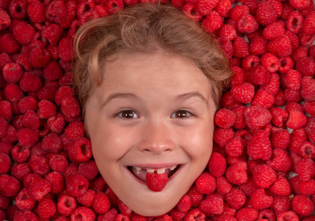 Summer fruits. The kids face with raspberries fruit and berries. Summer, pink red raspberry background.の写真素材