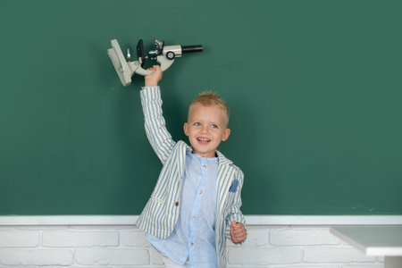 Little child with microscope. School child student learning in class, study english language at school.の写真素材