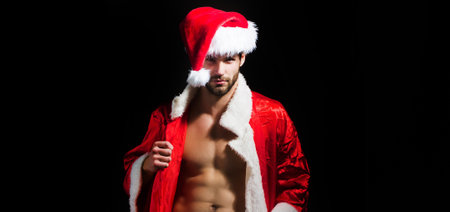 Santa men in santa hat. New year for adults. Muscle man at xmas. Santa with muscular body. Handsome sexy santa claus guy on black background.の写真素材