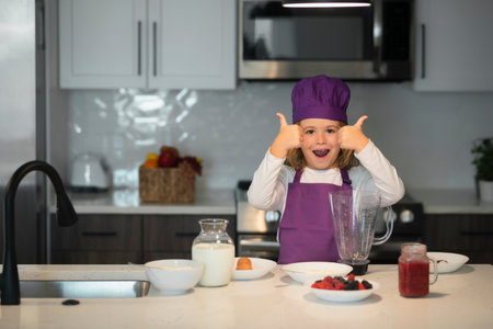 Child making tasty delicious. little boy in chef hat and an apron cooking in the kitchen.の写真素材