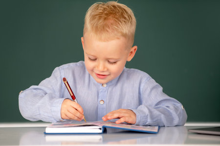 Little student child studying in classroom at elementary school. Pupil near chalkboard during lesson at primary school, close up portrait.の写真素材
