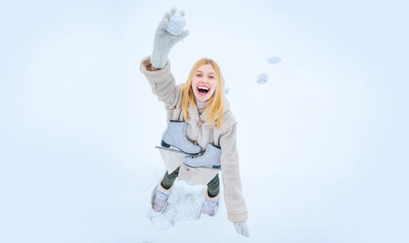 Girl throws snowballs. Snow games. Funny winter girl play with snow. Happy amazed girl in the snow...