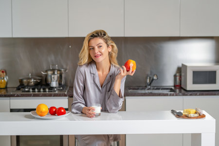 Apple and milk for breakfast. Beautiful woman have breakfast with healthy food in a cozy kitchen.の写真素材