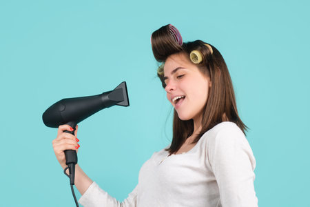 Woman with hair dryer. Beautiful girl with straight hair drying hair with professional hairdryer isolated in studio.の写真素材
