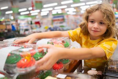 Kid choosing cakes, cupcake muffin. Shopping in supermarket or grocery store. Child buy food.の写真素材