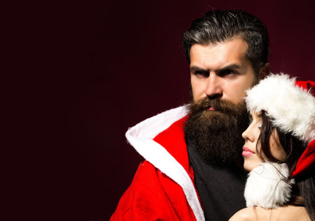Close up portrait of couple in Christmas hat. Christmas couple in love on dark red isolated studio background.の写真素材