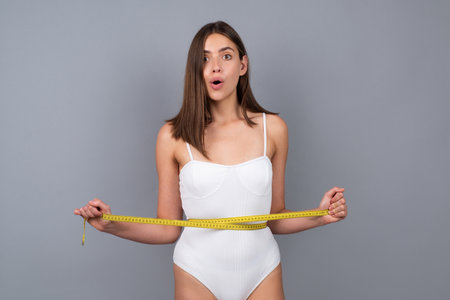Woman waist with tape, weight loss. Female model body care. Woman holding the meter with hands and measuring waist.の写真素材