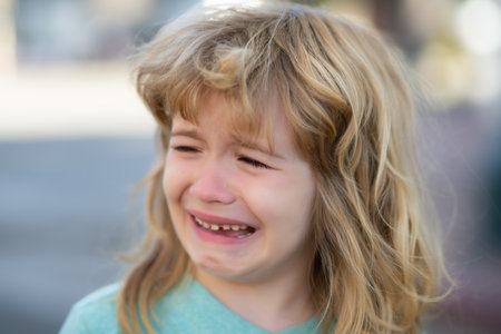 Portrait of crying kid with tears weeping emotion, hurt in pain. Tear drops on cheek.の写真素材